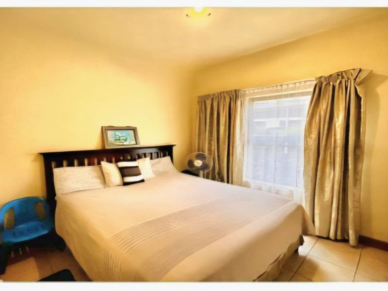 A standard bedroom featuring tiled flooring and a built-in wardrobe, offering a functional space with natural light.