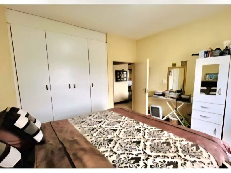A bedroom featuring built-in cupboards and neutral wall finishes, offering a functional space with potential for modernization.