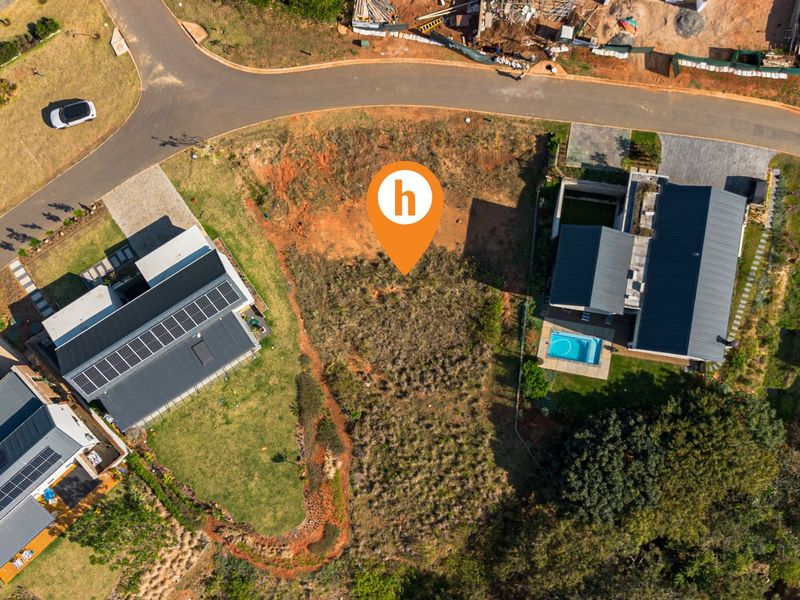 Aerial view of a vacant residential plot situated between two existing modern homes in a developed estate.