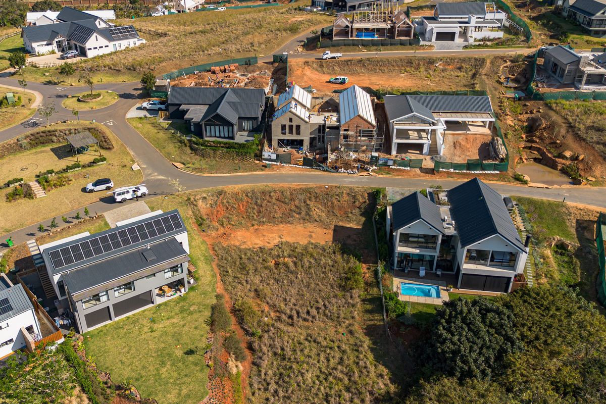 An aerial view of a vacant residential plot situated within a developed estate, surrounded by modern homes and established infrastructure.