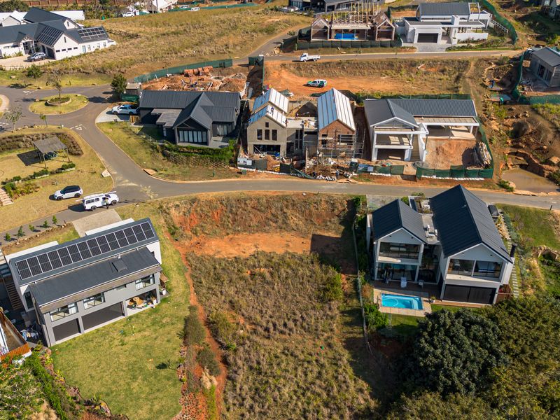 An aerial view of a vacant residential plot situated within a developed estate, surrounded by modern homes and established infrastructure.