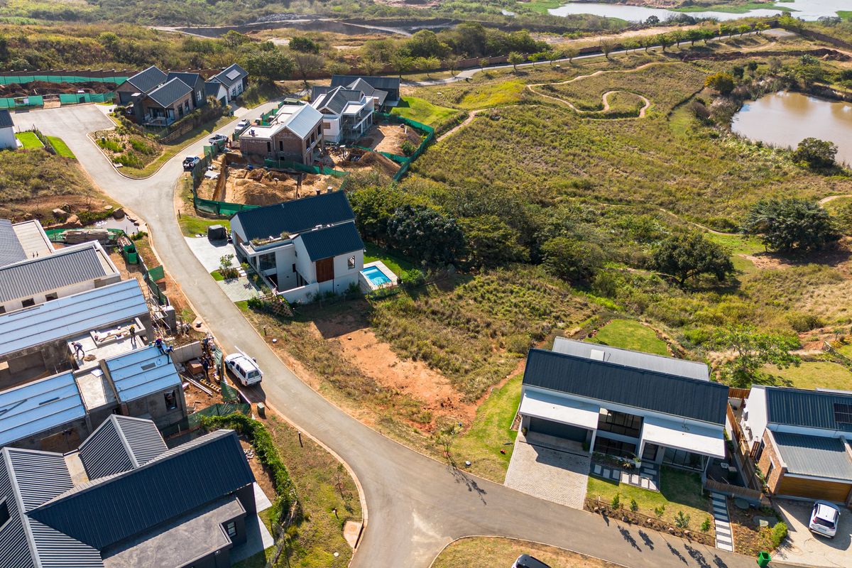 Aerial view of a residential estate development featuring modern homes, paved roads, and surrounding natural landscape.