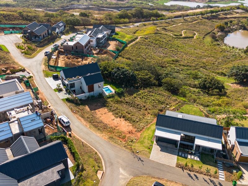 Aerial view of a residential estate development featuring modern homes, paved roads, and surrounding natural landscape.