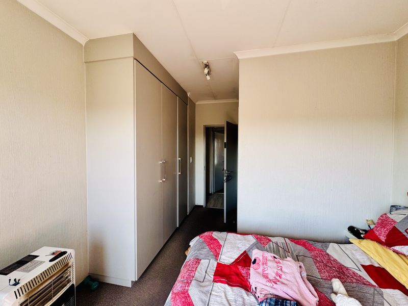 A bedroom featuring built-in cupboards, carpeted flooring, and coved ceiling details, providing a functional living space.