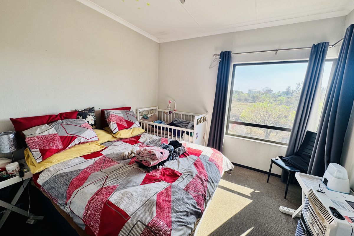 A functional bedroom featuring a large window that provides natural light and views, finished with carpeted flooring and standard ceiling lighting.