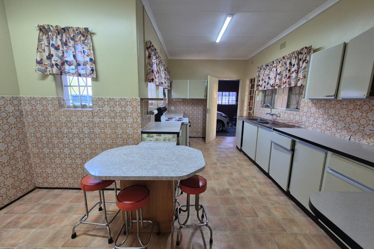 A dated kitchen featuring original cabinetry, tiled splashbacks, and a central breakfast nook, offering significant potential for a modern renovation.