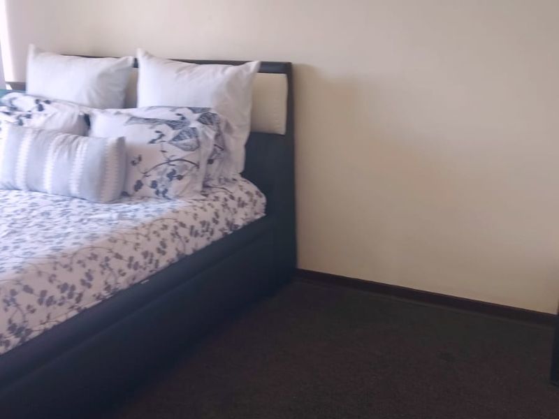 A simple bedroom featuring dark carpet flooring and neutral wall finishes, providing a functional and blank canvas for personalization.