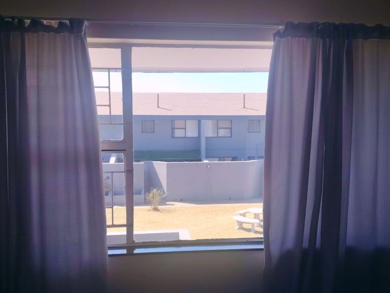 A view from an interior window looking out onto a residential courtyard and neighboring townhouse units.