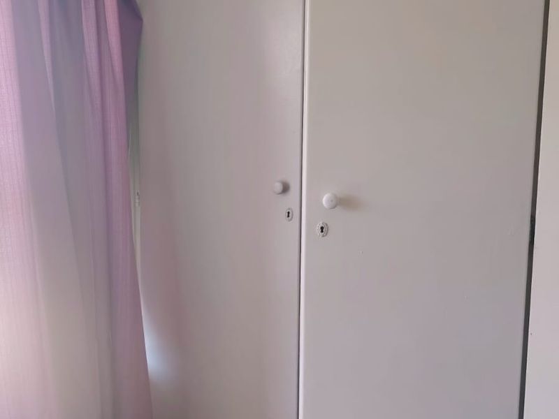 A bedroom interior featuring built-in cupboards with visible wear and tear on the doors.