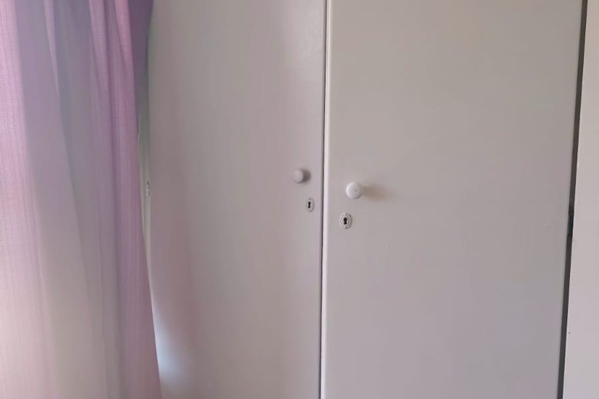 A bedroom interior featuring built-in cupboards with visible wear and tear on the doors.