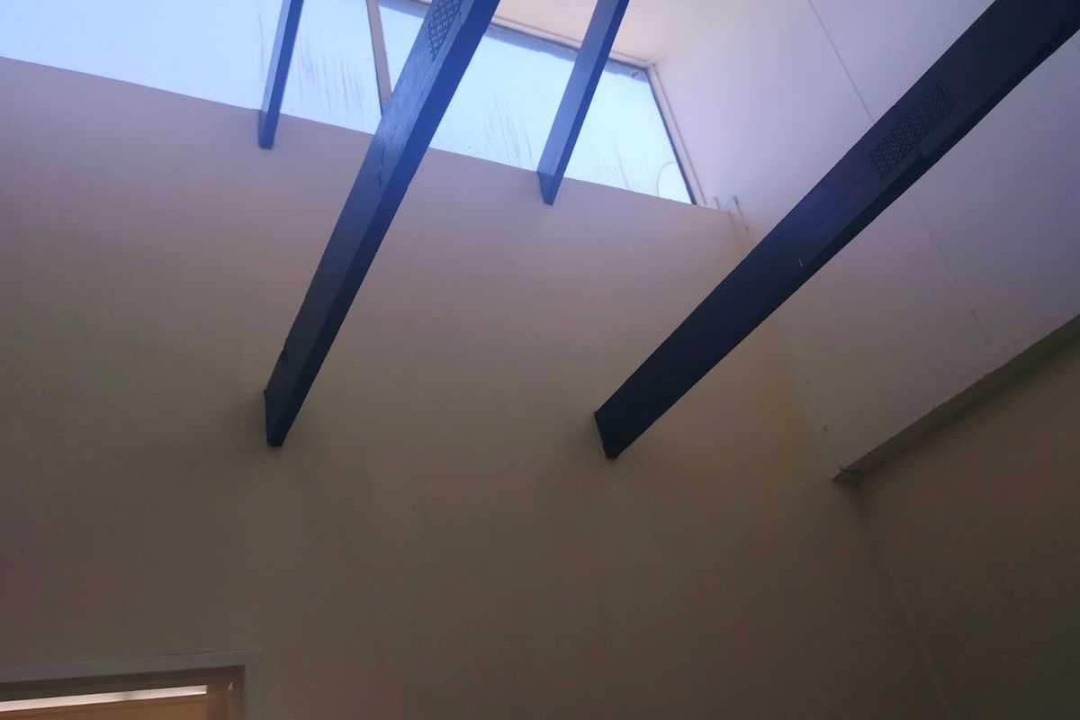 A high-ceilinged interior space featuring exposed timber beams and a large skylight, providing ample natural light.