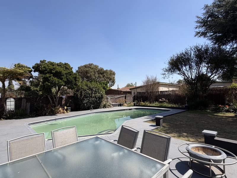 Spacious outdoor entertainment area featuring a swimming pool, paved patio space, and established garden surroundings, ideal for outdoor living.