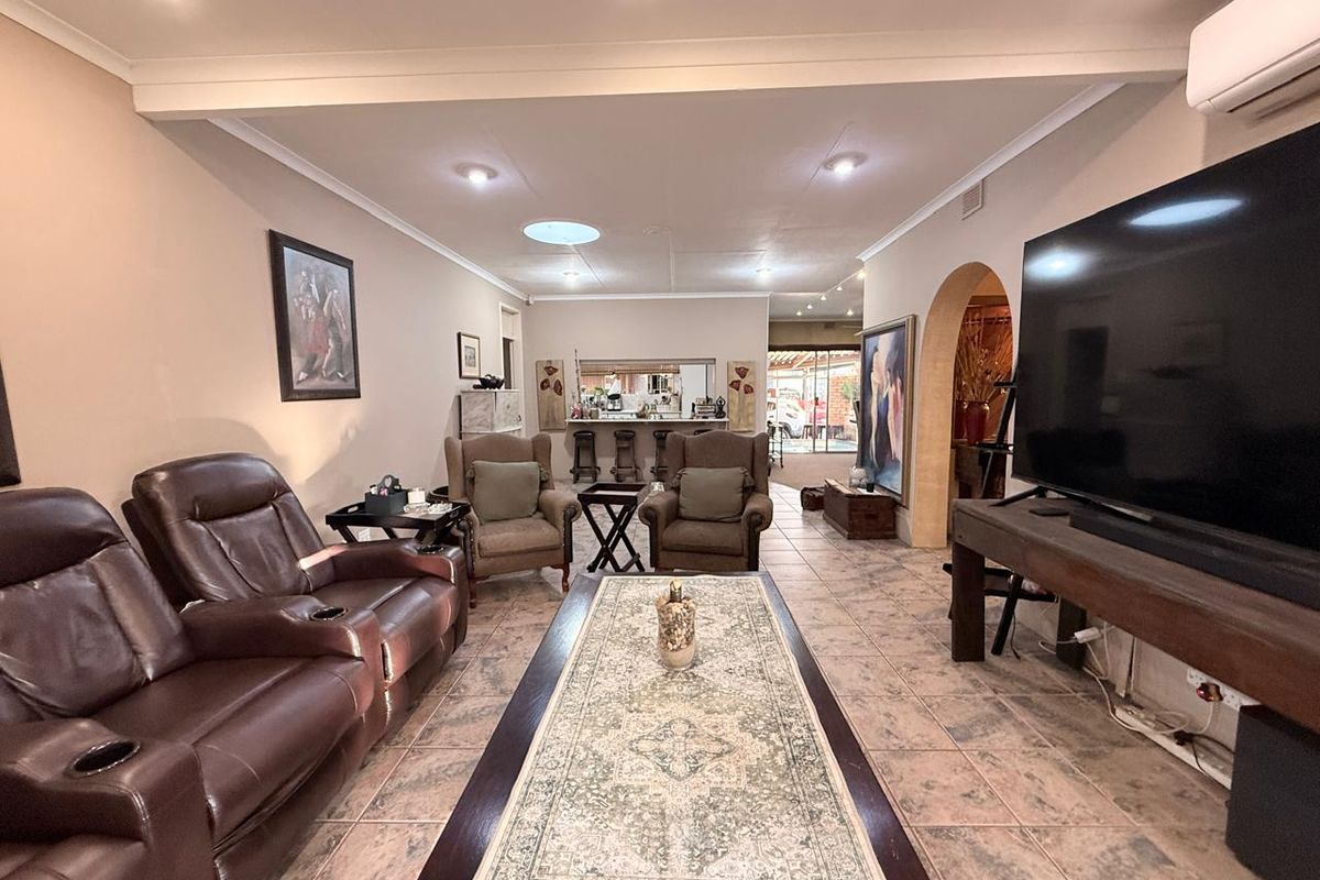 Spacious living room featuring tiled flooring, recessed lighting, a skylight, and an integrated bar area with an arched entryway.