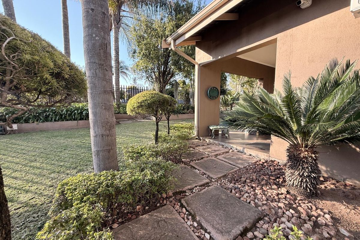 A well-maintained rear garden featuring a covered patio area, paved stone walkway, and established landscaping.
