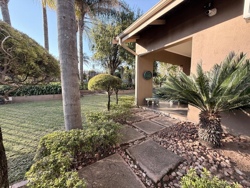 A well-maintained rear garden featuring a covered patio area, paved stone walkway, and established landscaping.
