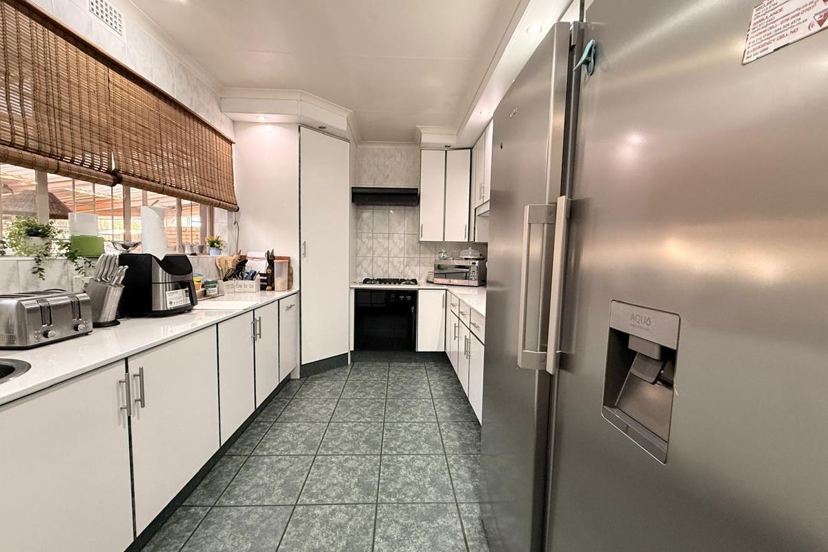 A functional galley-style kitchen featuring white cabinetry, tiled flooring, a gas hob, and an integrated oven with a tiled backsplash.