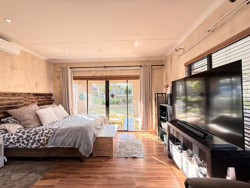 Spacious bedroom featuring laminate flooring, recessed lighting, and a sliding glass door providing direct access to the rear garden area.