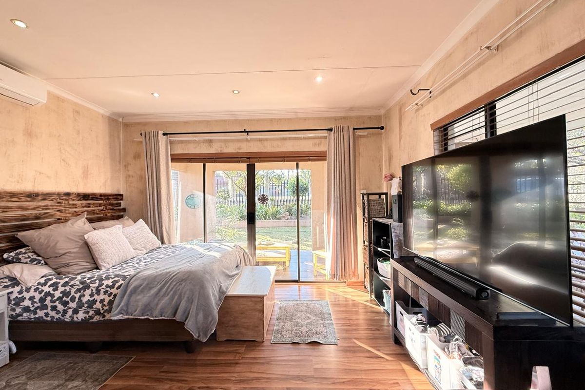 Spacious bedroom featuring laminate flooring, recessed lighting, and a sliding glass door providing direct access to the rear garden area.