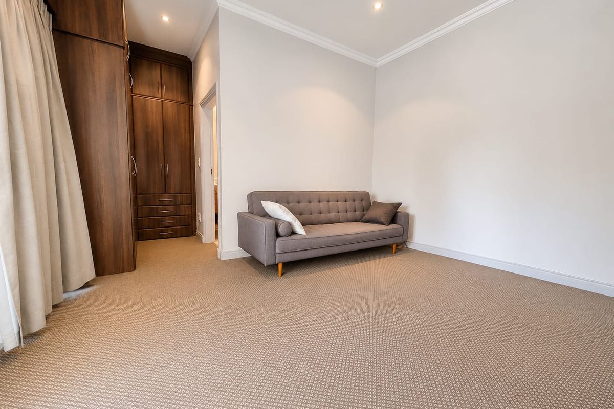 A well-maintained bedroom featuring neutral carpeting, built-in wooden cabinetry, and recessed ceiling lighting.