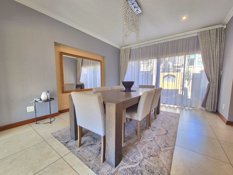 A well-maintained dining room featuring tiled flooring, recessed lighting, and large sliding glass doors that provide ample natural light.