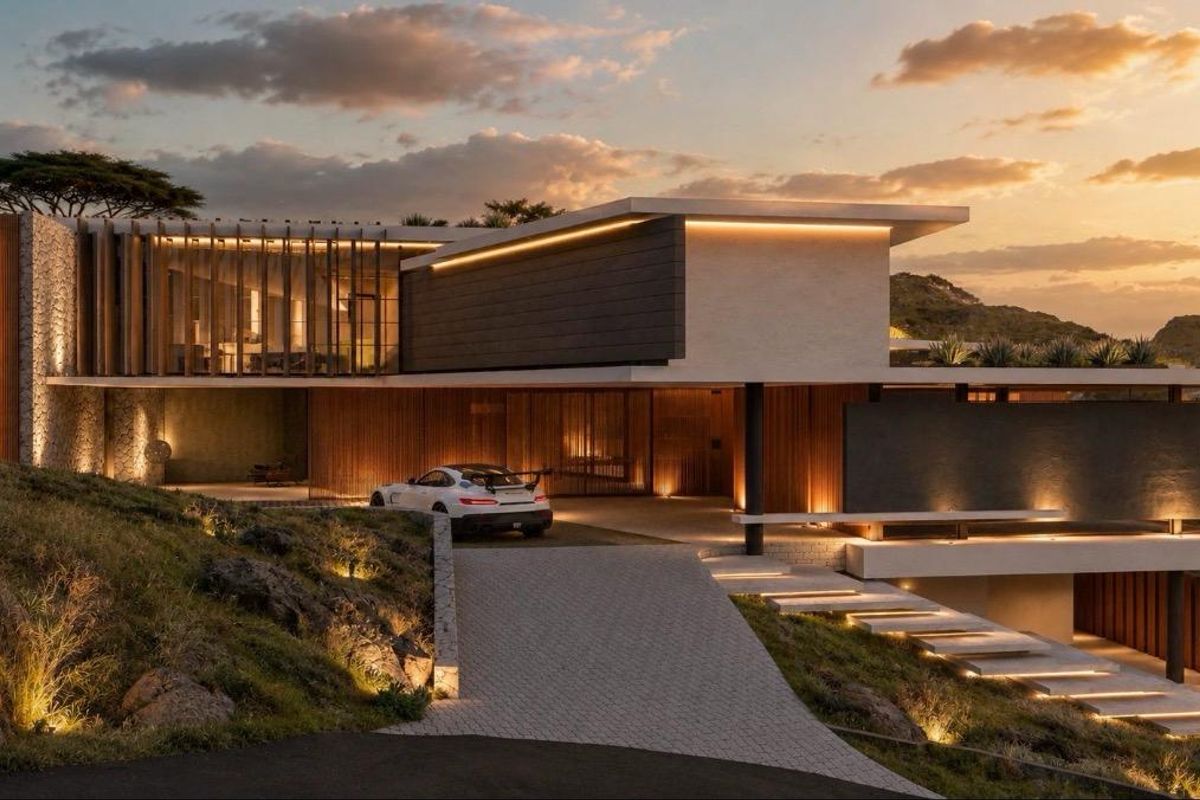 A modern luxury residence featuring stone cladding, cantilevered architecture, and integrated landscape lighting, set against a scenic hillside backdrop.