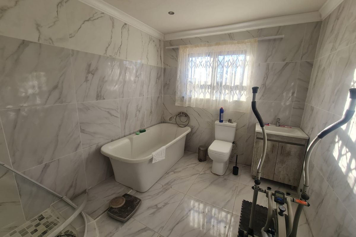 Modern bathroom featuring marble-look wall and floor tiles, a freestanding bathtub, a separate shower enclosure, and a vanity cabinet with basin.
