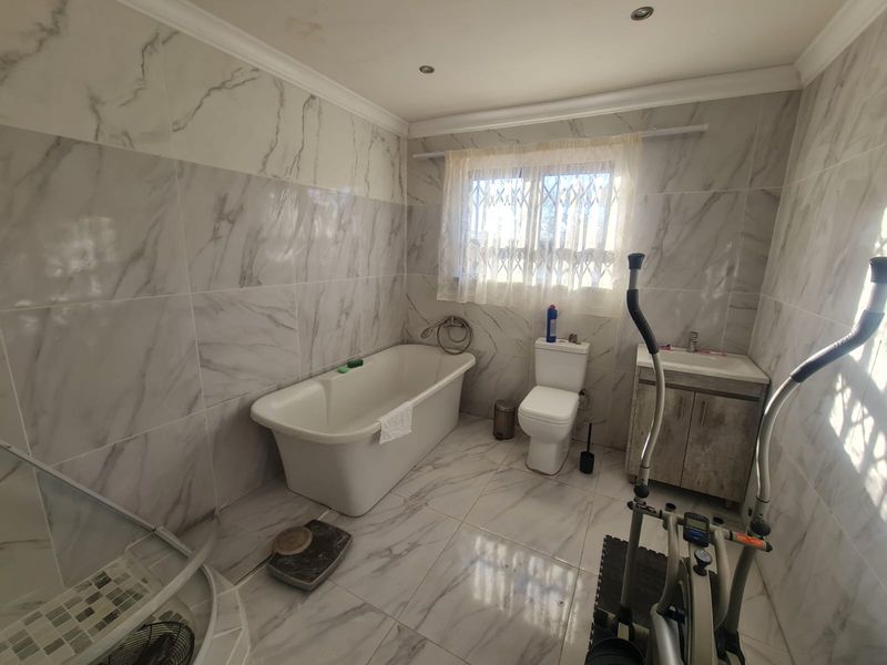 Modern bathroom featuring marble-look wall and floor tiles, a freestanding bathtub, a separate shower enclosure, and a vanity cabinet with basin.