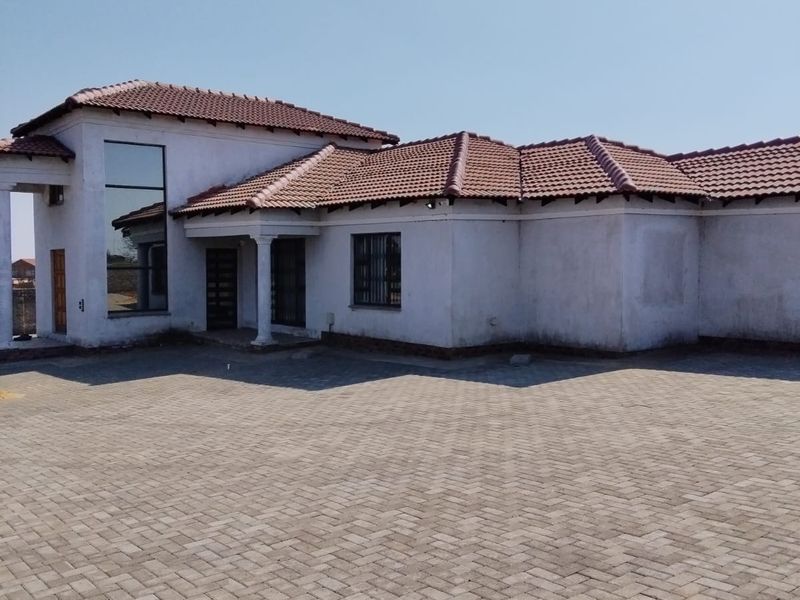 Front view of a single-story house featuring a tiled roof, paved driveway, and a prominent glass window at the entrance.