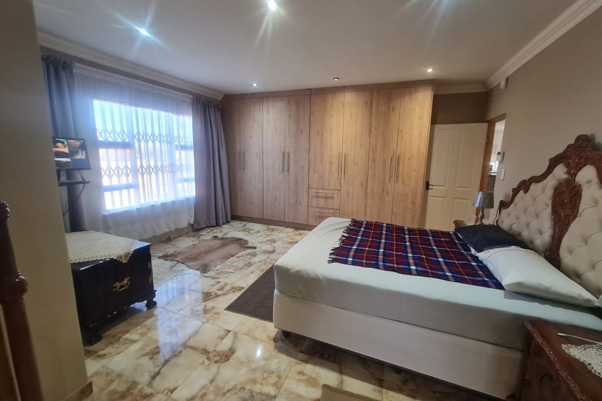 Spacious bedroom featuring extensive built-in wooden cabinetry, polished marble-look tiled flooring, and recessed ceiling lighting.