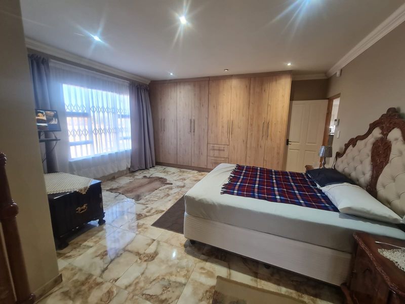 Spacious bedroom featuring extensive built-in wooden cabinetry, polished marble-look tiled flooring, and recessed ceiling lighting.