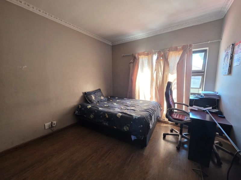 A functional bedroom featuring laminate flooring and decorative ceiling cornicing, offering a neutral base ready for personalization.