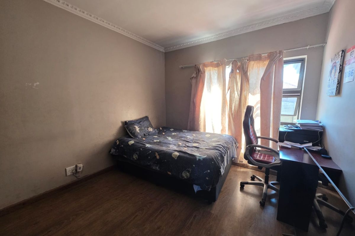 A functional bedroom featuring laminate flooring and decorative ceiling cornicing, offering a neutral base ready for personalization.