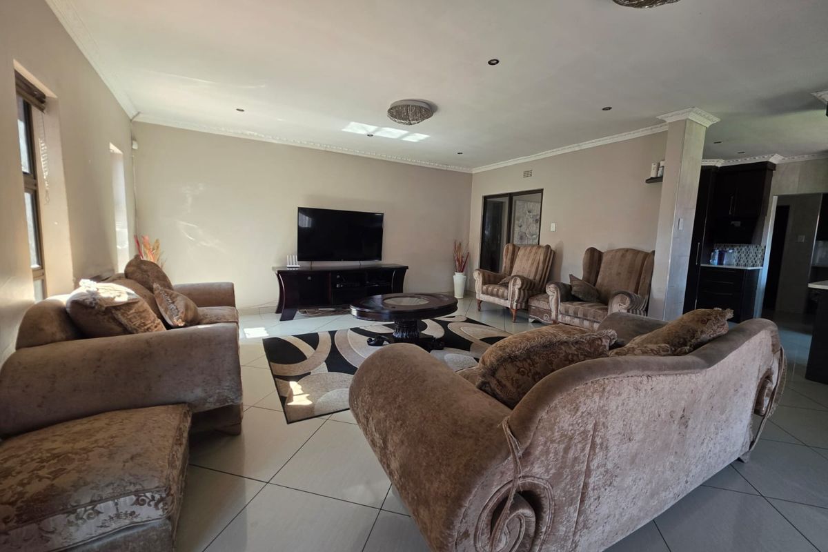 Spacious living room featuring large format floor tiles, recessed downlighting, and decorative ceiling cornices, providing a comfortable and well-maintained area for relaxation.