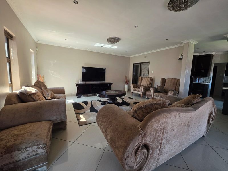 Spacious living room featuring large format floor tiles, recessed downlighting, and decorative ceiling cornices, providing a comfortable and well-maintained area for relaxation.