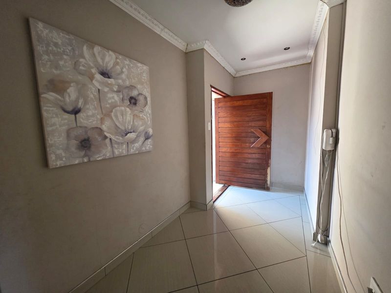 A bright entrance hall featuring tiled flooring, crown molding, recessed lighting, and a solid wood front door with an integrated intercom system.