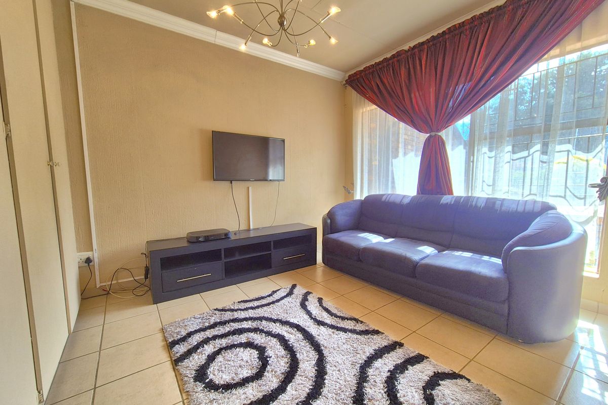 A living room featuring tiled flooring, a built-in cupboard, and a ceiling light fixture, providing a functional space for relaxation.