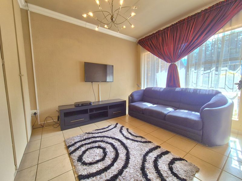 A living room featuring tiled flooring, a built-in cupboard, and a ceiling light fixture, providing a functional space for relaxation.