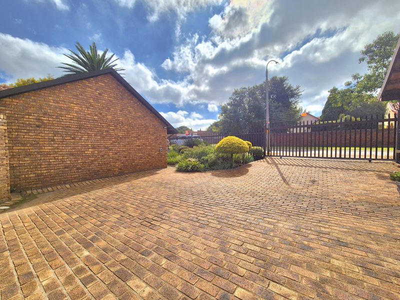 A well-maintained front driveway featuring brick paving, a secure electric gate, and perimeter electric fencing.