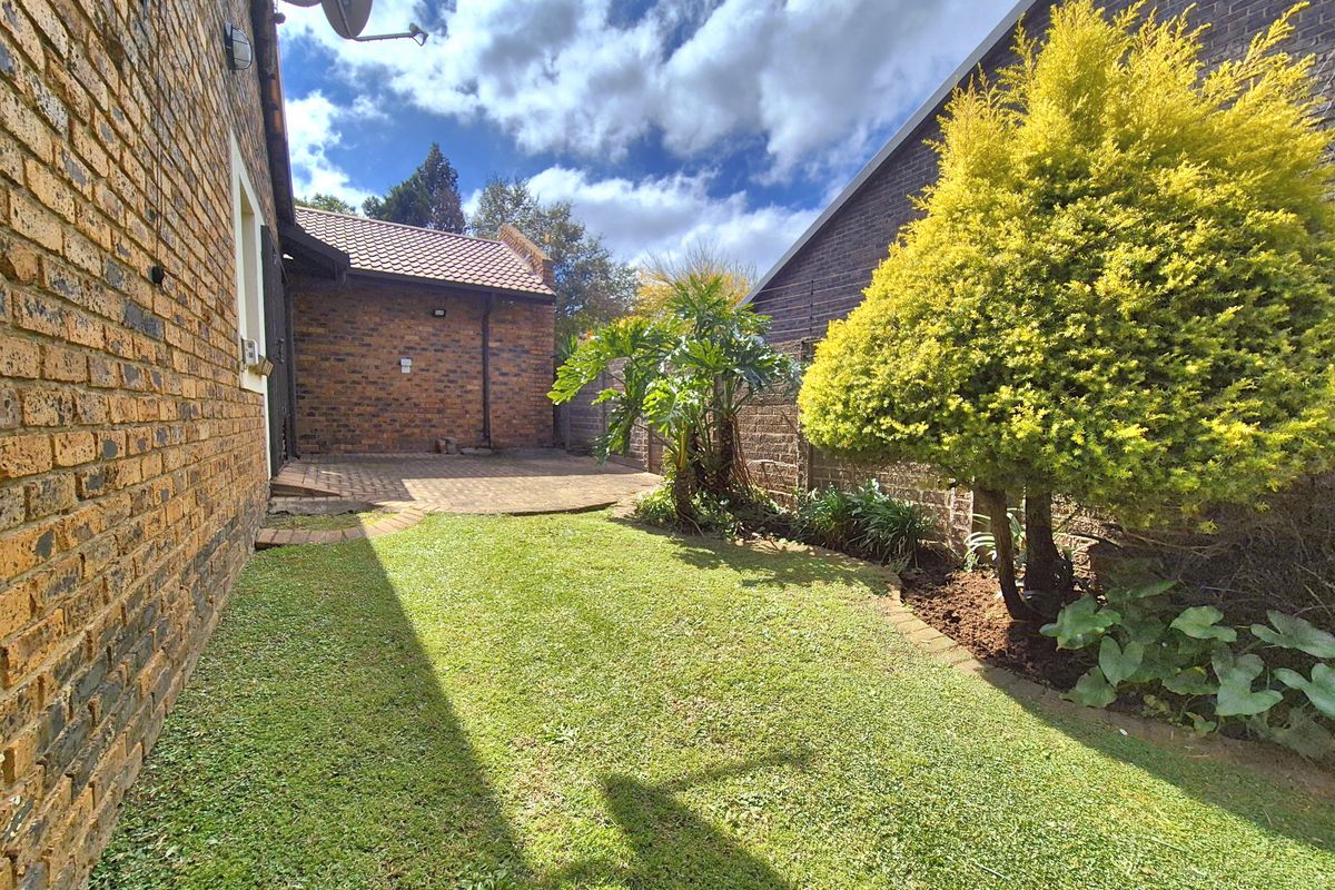 A private rear garden featuring a brick-paved patio area, established lawn, and perimeter brick boundary walls.