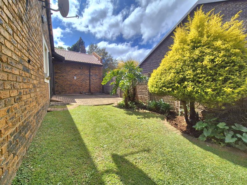 A private rear garden featuring a brick-paved patio area, established lawn, and perimeter brick boundary walls.