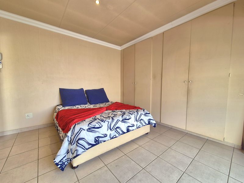 A bedroom featuring tiled flooring, coved ceilings, and extensive built-in cupboard storage.