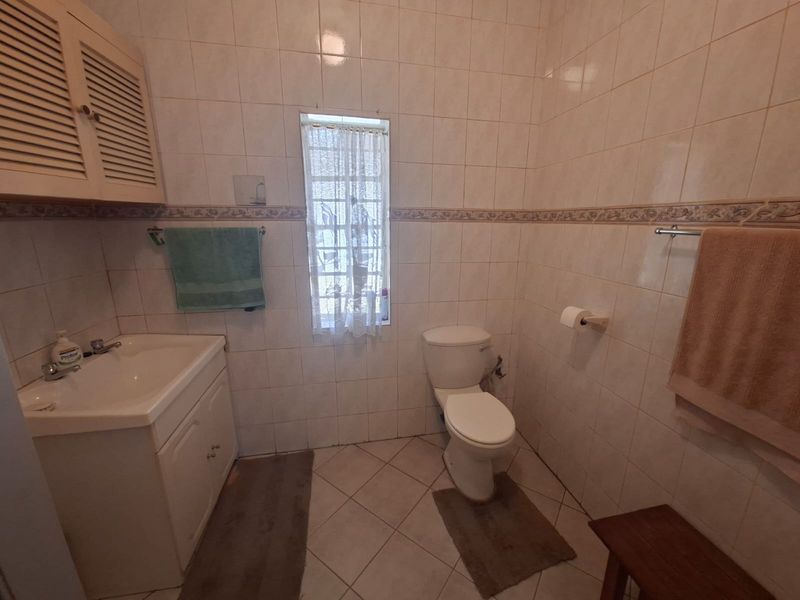 A functional bathroom featuring tiled walls and floors, a vanity cabinet with a basin, and a standard toilet.