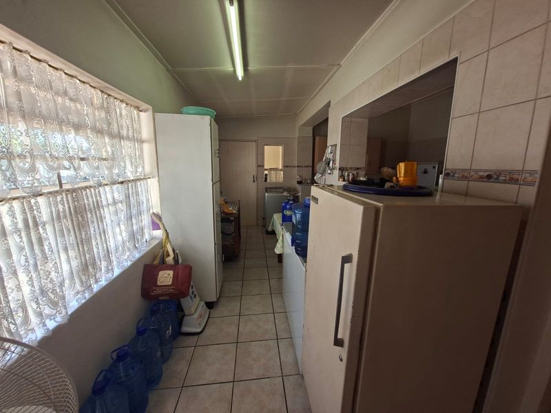A functional scullery or utility area featuring tiled flooring and wall splashbacks, providing additional workspace and storage adjacent to the main kitchen.
