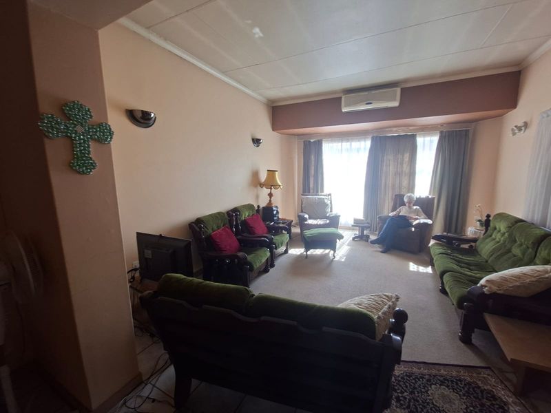 A spacious living room featuring wall-mounted air conditioning, wall sconces, and carpeted flooring, offering a comfortable and functional layout.