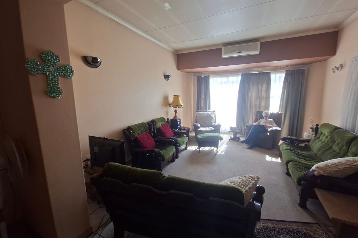 A spacious living room featuring wall-mounted air conditioning, wall sconces, and carpeted flooring, offering a comfortable and functional layout.