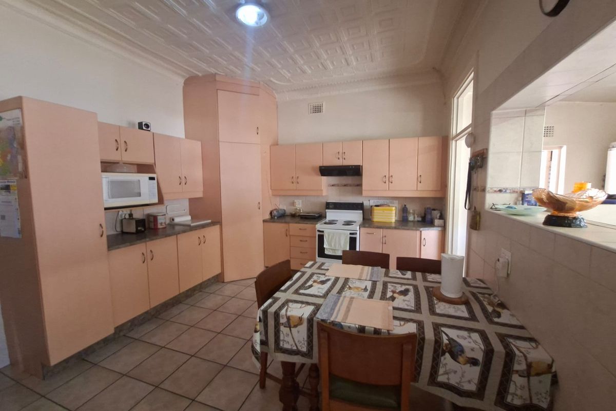A dated kitchen featuring original cabinetry, tiled flooring, and a classic pressed metal ceiling, offering potential for a modern renovation.