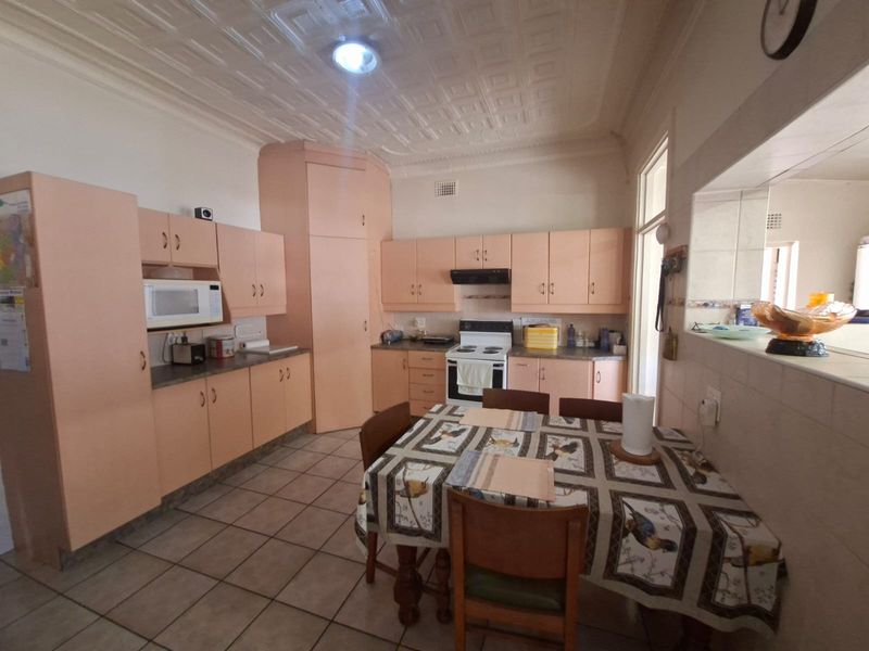 A dated kitchen featuring original cabinetry, tiled flooring, and a classic pressed metal ceiling, offering potential for a modern renovation.