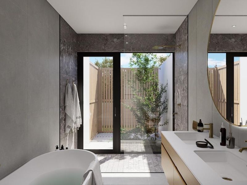 Modern luxury bathroom featuring a freestanding bathtub, double vanity with brass fixtures, and a seamless transition to a private outdoor courtyard.
