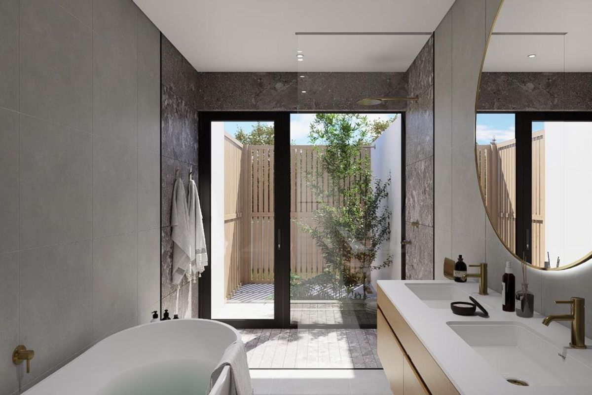 Modern luxury bathroom featuring a freestanding bathtub, double vanity with brass fixtures, and a seamless transition to a private outdoor courtyard.