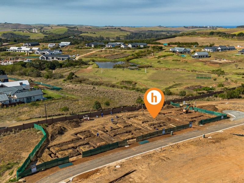 Aerial view of a residential construction site showing excavated foundations and perimeter fencing within a developing estate.